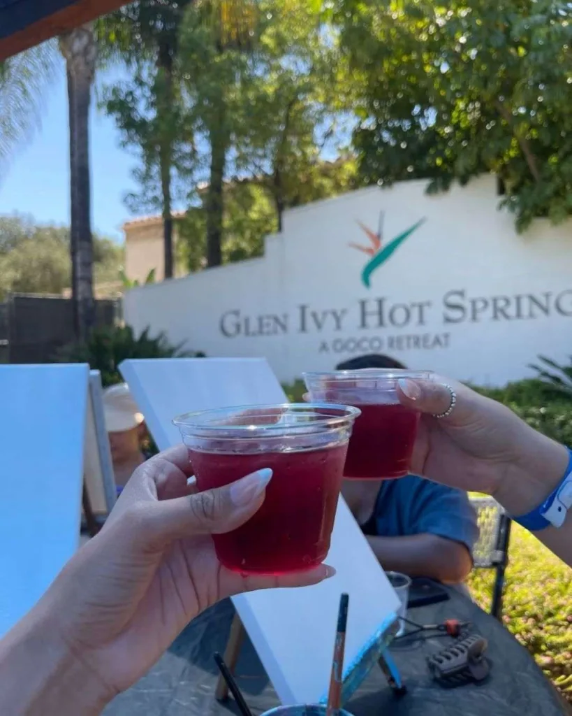 Two people toast with red drinks during a painting session at the Glen Ivy Hot Springs.