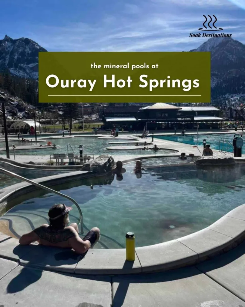 People relaxing in the mineral pools at Ouray Hot Springs with snowy mountains in the background.