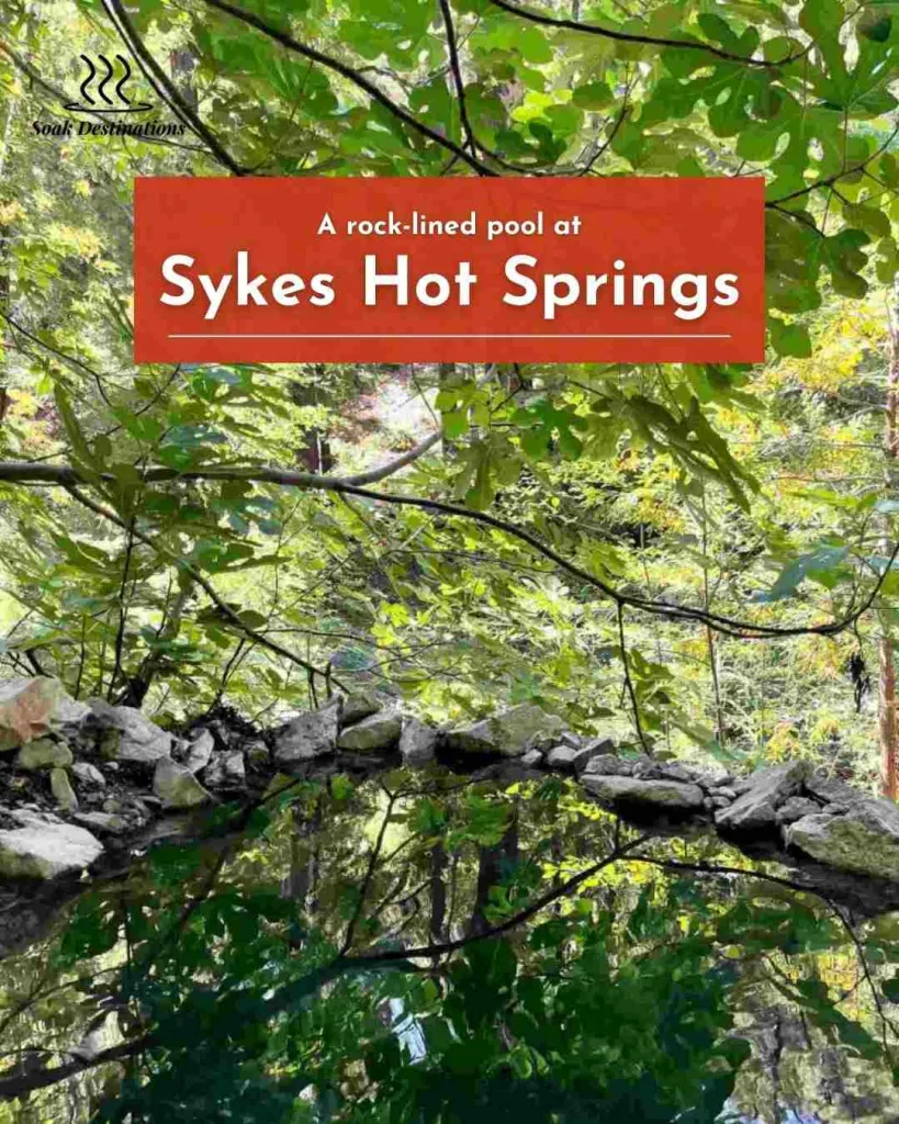 A rock-lined pool reflects lush green leaves and tall trees on the way to Indian Hot Springs.