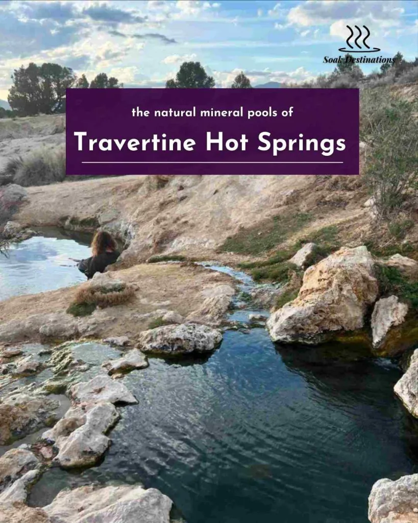 A person soaks in the natural mineral pools of Travertine Hot Springs surrounded by desert hills.