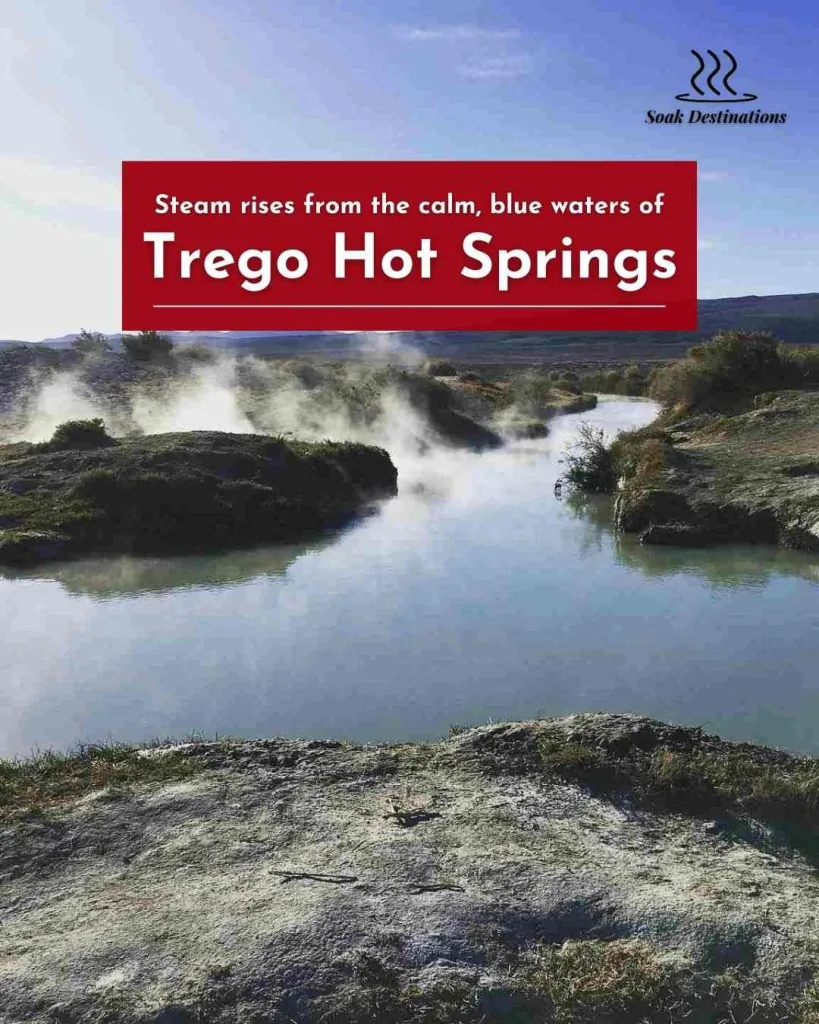 Steam rises from the calm, blue waters of Trego Hot Springs under a clear sky.