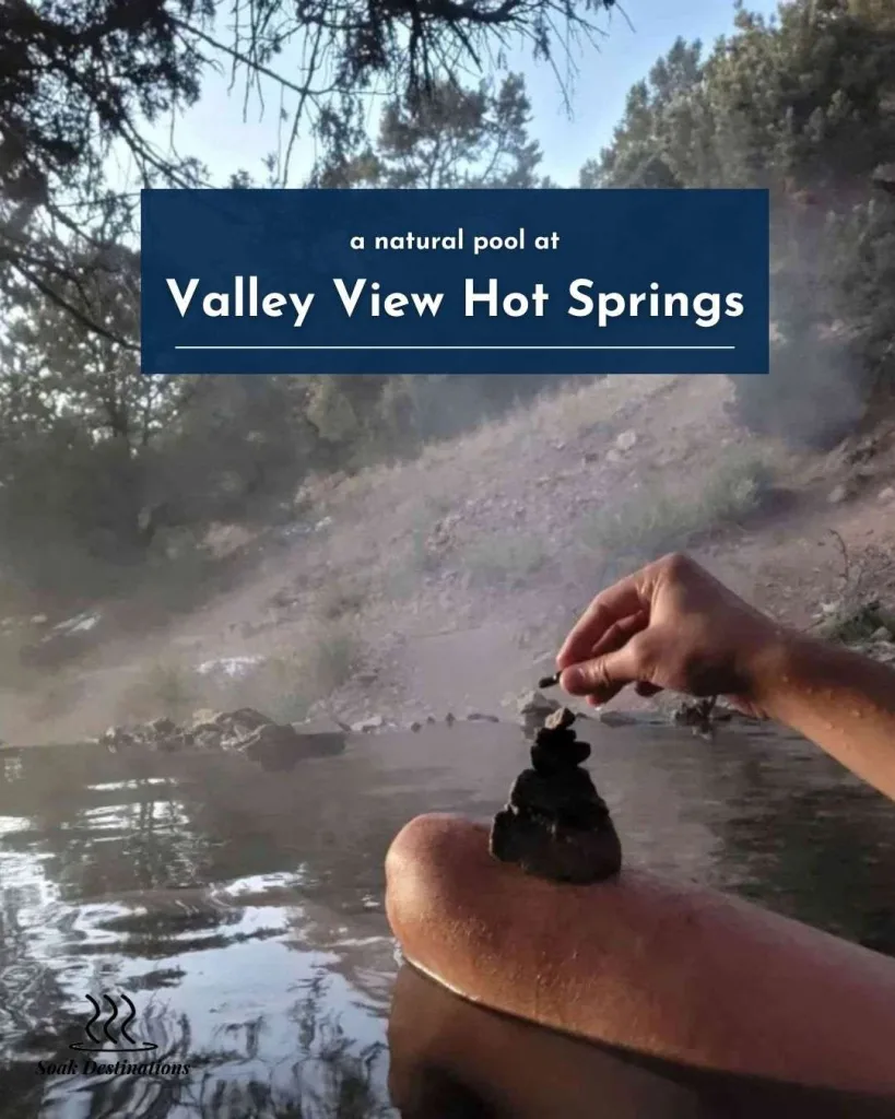 A visitor stacks small stones while soaking in a natural pool at Valley View Hot Springs.