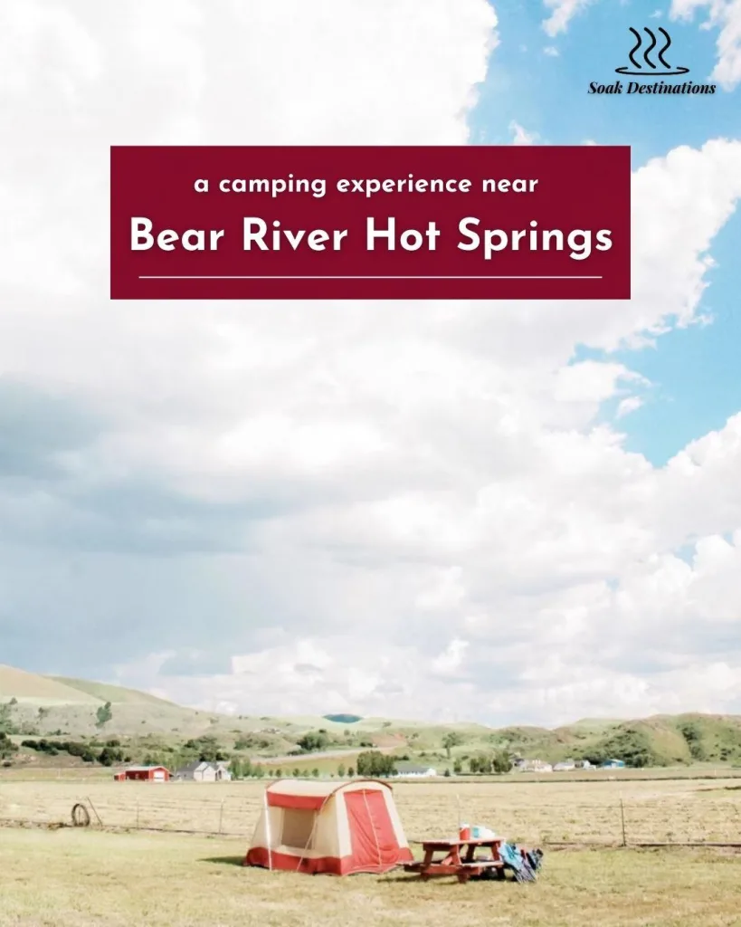 A red and white tent pitched in a grassy field with rolling hills in the background, offering a camping experience near Bear River Hot Springs.