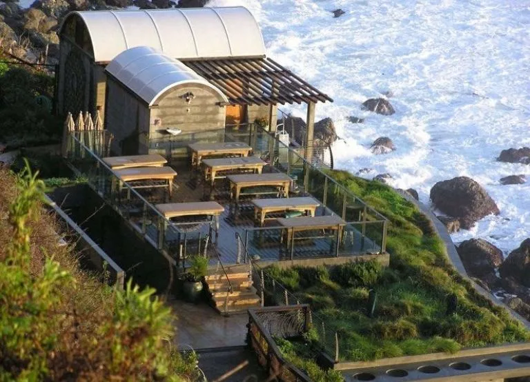 Oceanfront wooden deck restaurant overlooking waves at Esalen Hot Springs.