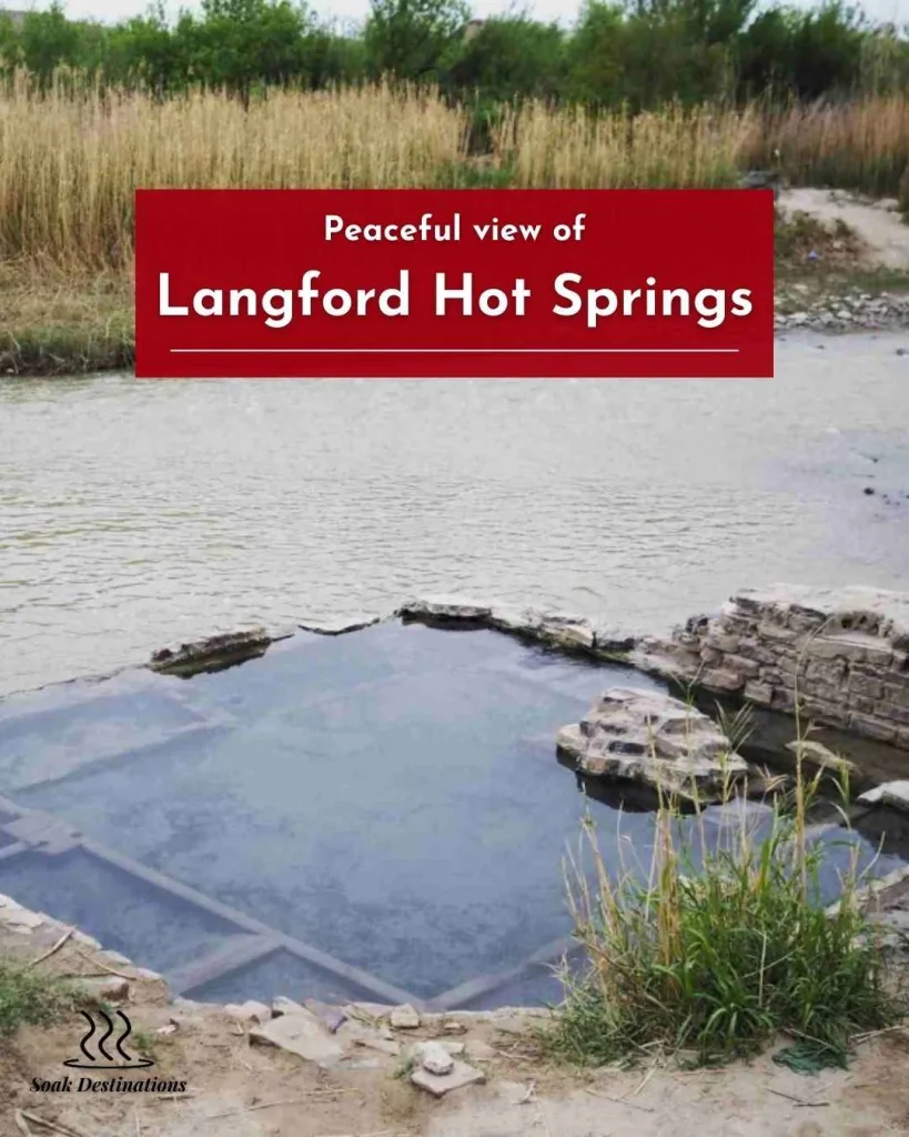 Peaceful view of Langford Hot Springs with calm mineral water pool surrounded by grass and natural riverbank.