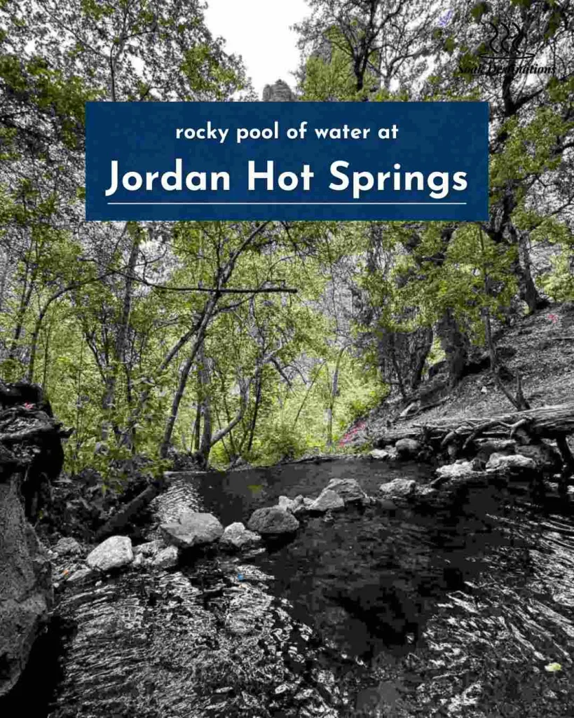 Lush green trees overhang a dark, rocky pool of water at the secluded Jordan Hot Springs location.