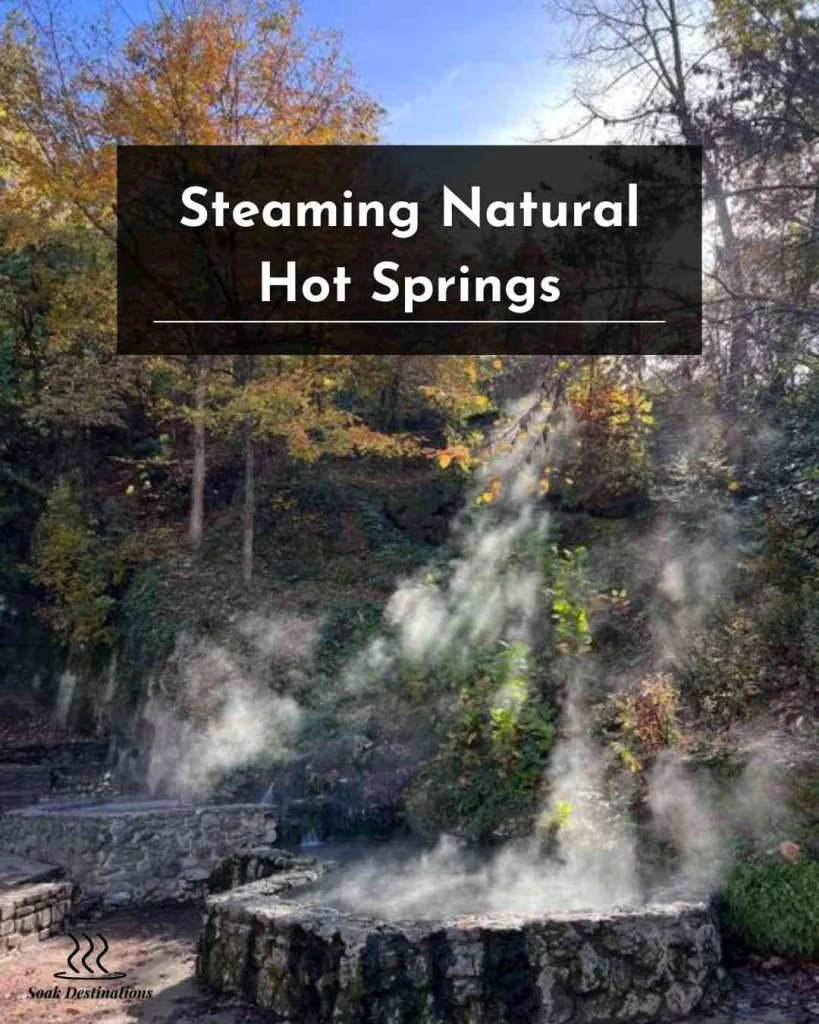 Steaming natural hot springs surrounded by vibrant autumn trees in Hot Springs National Park. 